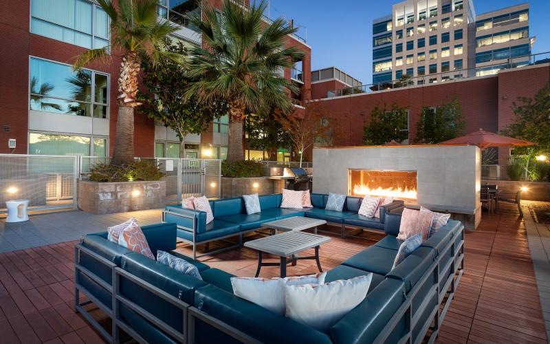 an outdoor lounge with couches and a fireplace